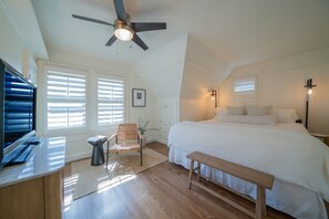 Relax in this serene bedroom with a large bed, ceiling fan, and comfortable bench.