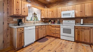 A wooden kitchen with a microwave, stove, and dishwasher.