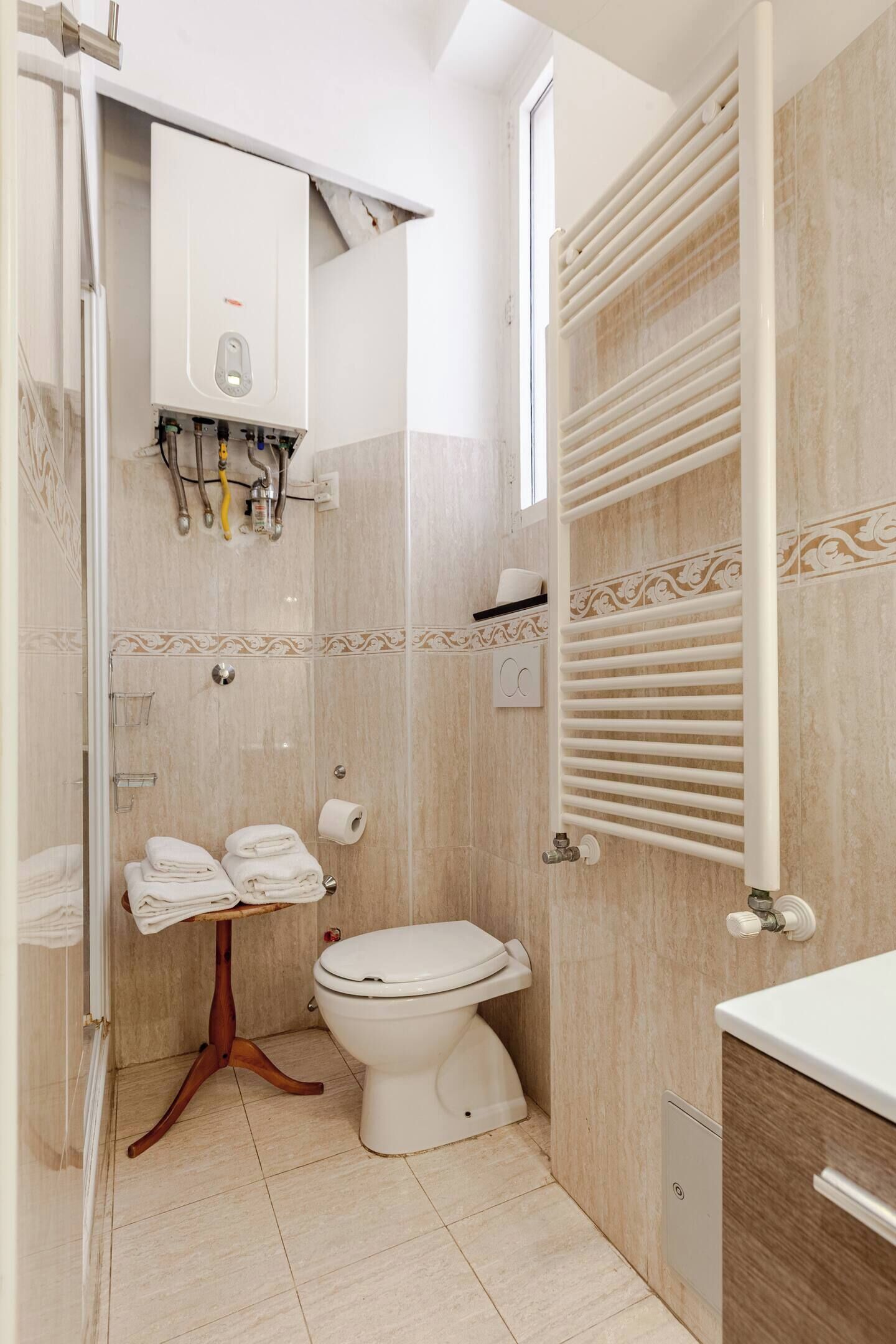 Et badeværelse med toilet, håndklædestativ, bruser og radiator.