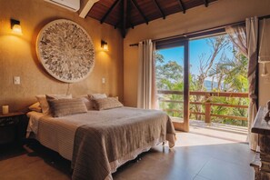 Une chambre avec un grand lit, un élément de décoration circulaire au mur et une vue sur la verdure grâce à une porte coulissante.
