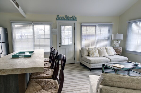 A living room with a sofa, a coffee table, and a dining area with chairs and a table.