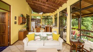 Un salón amplio con un sofá blanco, techo de madera y ventanas grandes.
