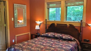 Una camera da letto con un letto in legno, due lampade sui comodini, una finestra vista sul verde e una porta.