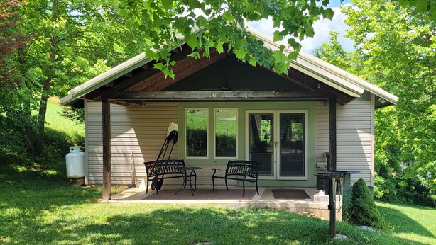 Un piccolo chalet con veranda, due sedie e un tavolo.