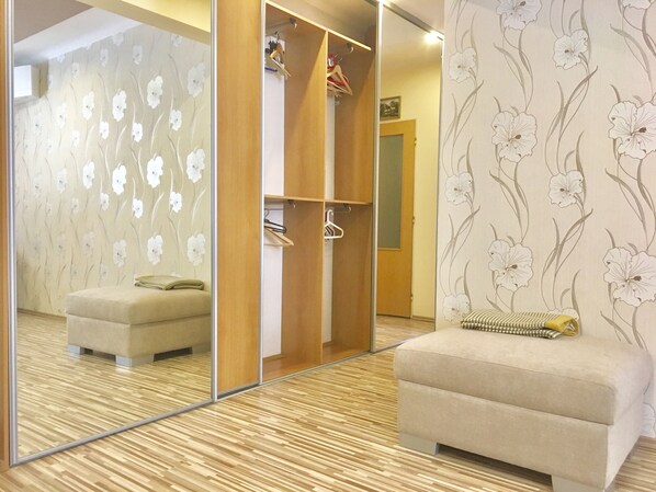 A room with a mirrored wardrobe, a cushioned bench, and a floral wallpaper pattern.