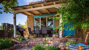 A patio with a covered seating area, stone planters, and a colorful birdbath.