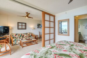 Una habitación con cama, sofá, televisión y ventilador de techo.