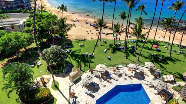 A resort with a pool, beach, and palm trees.