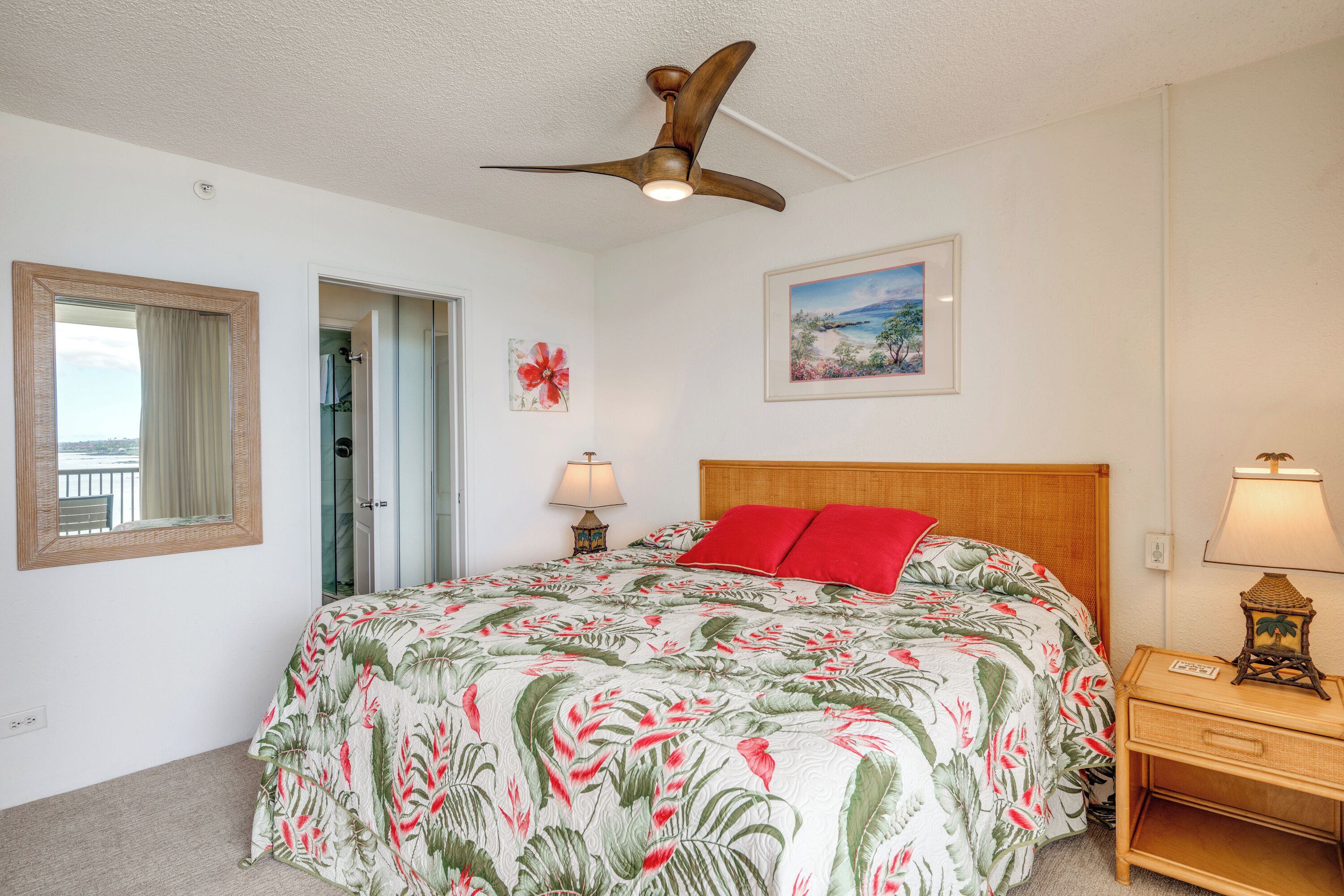 Une chambre à coucher avec un lit, un ventilateur de plafond, une table de chevet, une lampe, un tableau encadré et une fenêtre donnant sur un beau paysage.