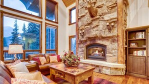 Una sala de estar acogedora con chimenea de piedra, sofá de cuero y estantería.