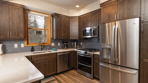 Una cucina moderna con mobili in legno, elettrodomestici in acciaio inossidabile, forno integrato e una finestra vista alberi.