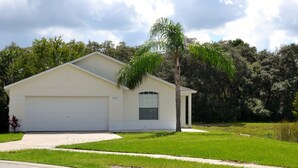 A single-story house with a garage, a small attached structure, and a well-maintained lawn. - Beautiful Waterside Villa For Rent In Orlando (Clermont)