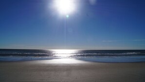 A beach with a clear sky and sunlight reflecting off the water.