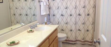 A bathroom with a double sink vanity, a toilet, and a shower curtain with a floral pattern.