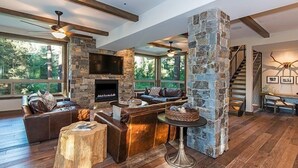 A spacious living area with a stone fireplace, leather sofas, and a stone pillar.