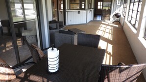 Un espace intérieur spacieux, aménagé avec des meubles en osier, une table sur laquelle est posé un rouleau de papier toilette et un ventilateur de plafond.