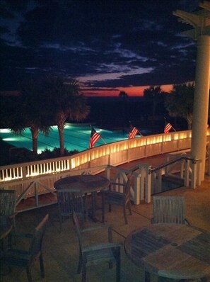 A deck with outdoor seating and a view of a pool at dusk. - "The Palms" is nestled on a secluded half acre in the forest.  ThePalmsHouse.com (Bald Head Island)