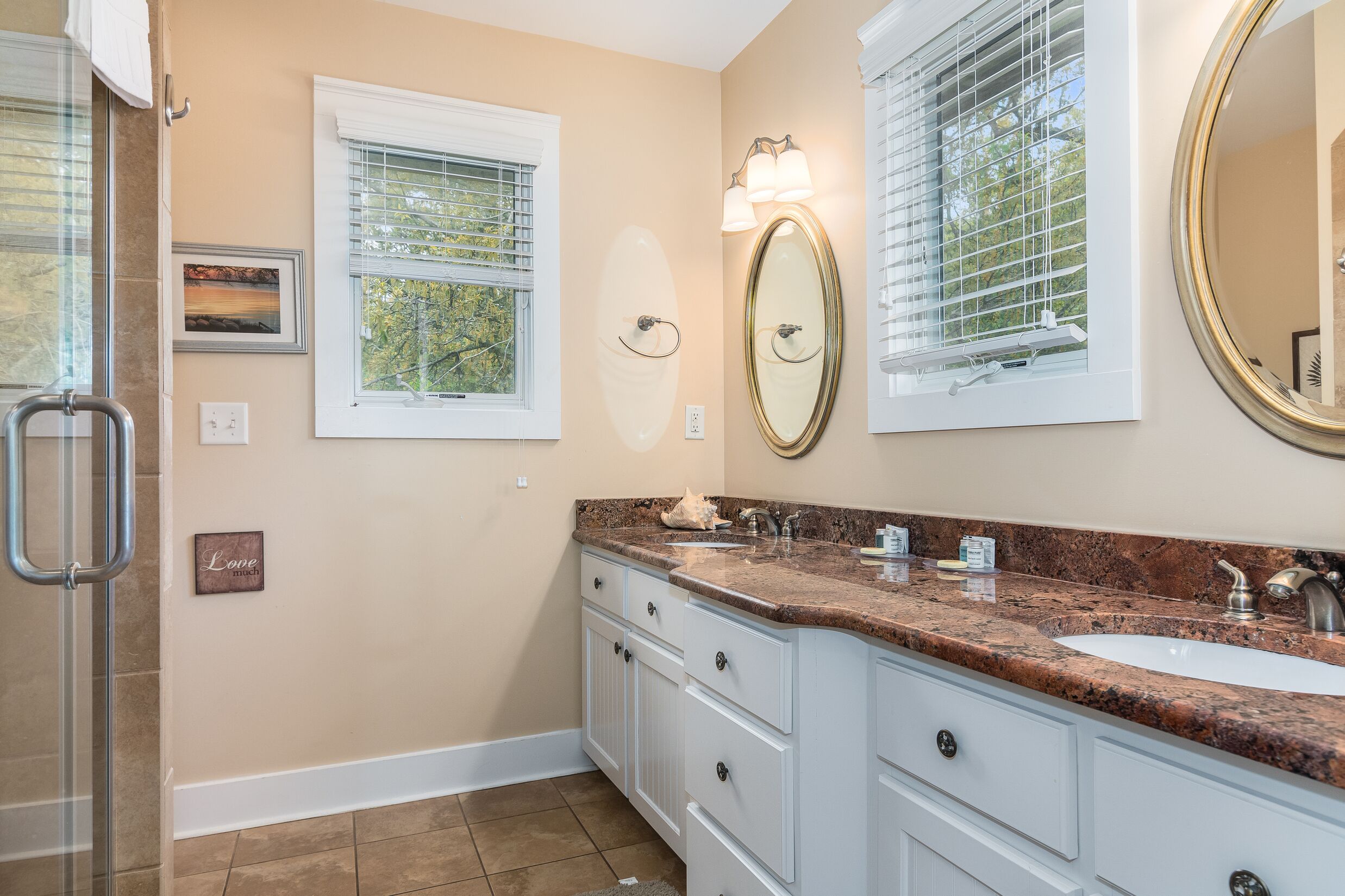 A bathroom with two sinks, a large mirror, and a window with blinds.