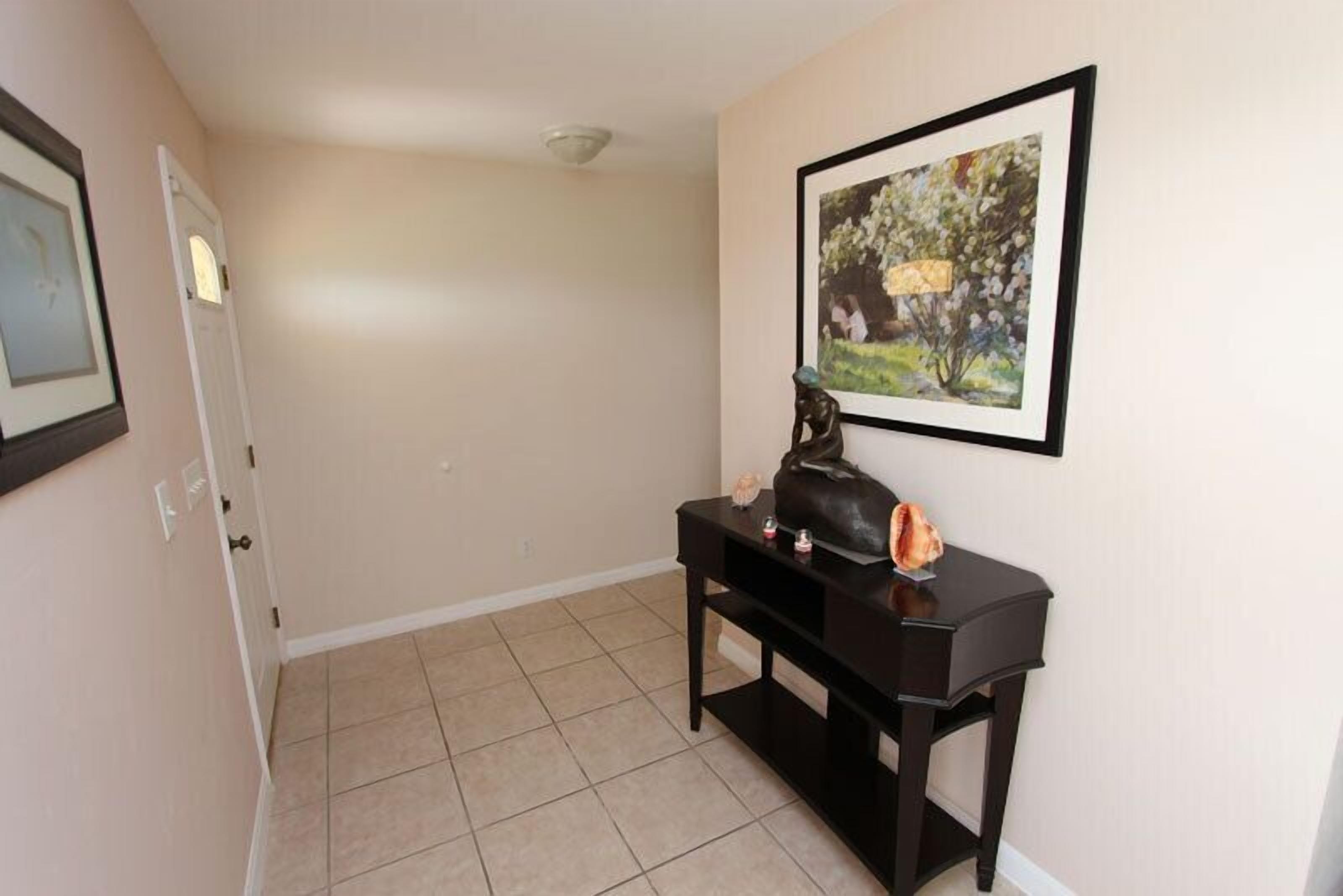 A hallway with a door, a framed picture on the wall, and a small table with a handbag and decorative items.