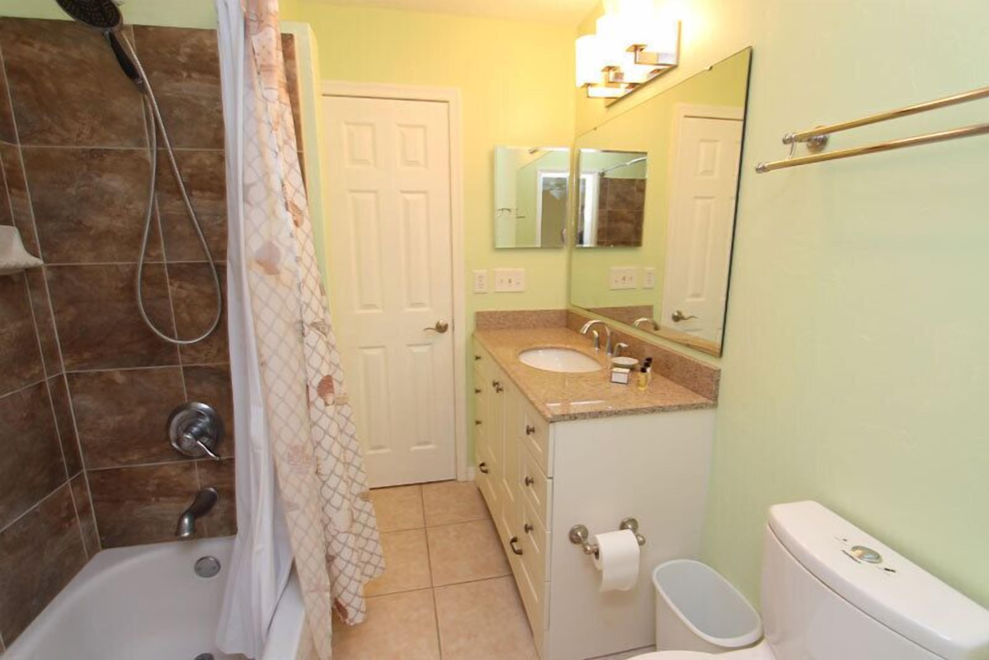 Un bagno con vasca, servizi igienici, lavandino e tenda doccia.