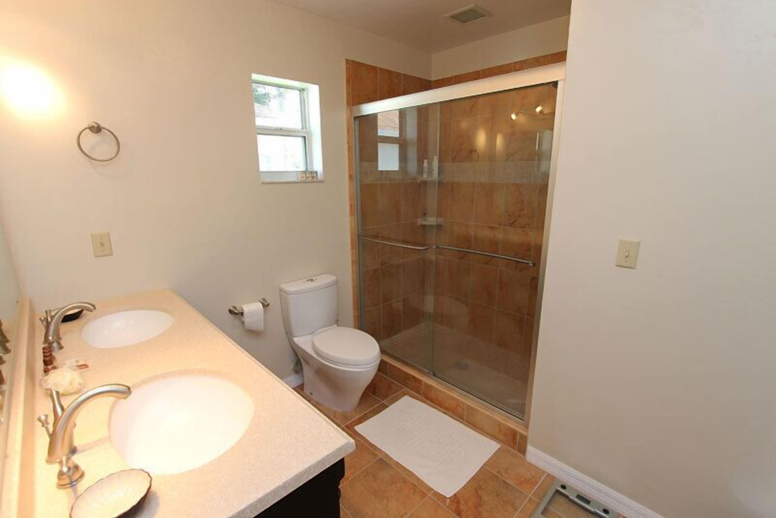 A bathroom with two sinks, a toilet, and a glass-enclosed shower.