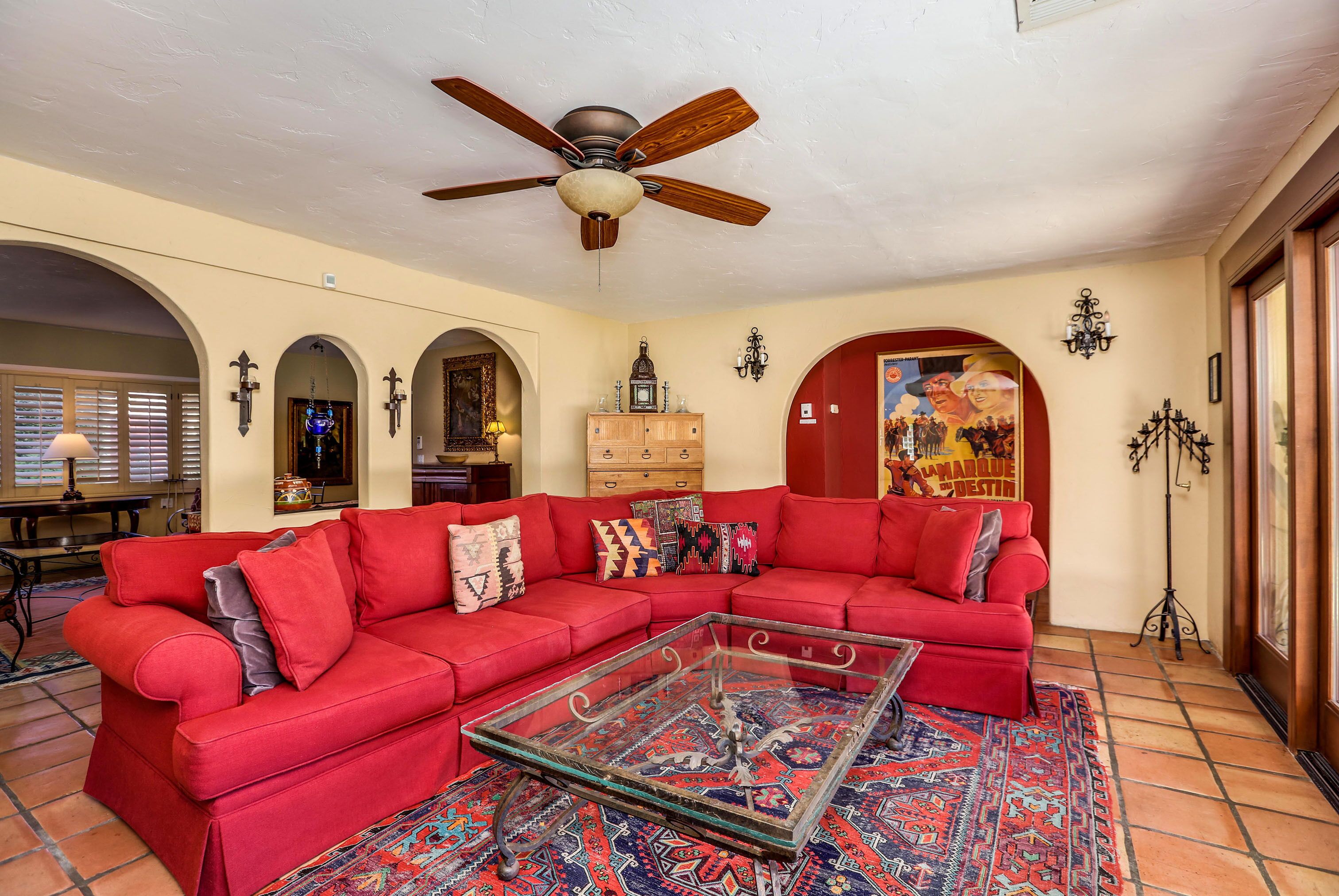 A living room with a red sectional sofa, a glass coffee table, and a patterned rug.