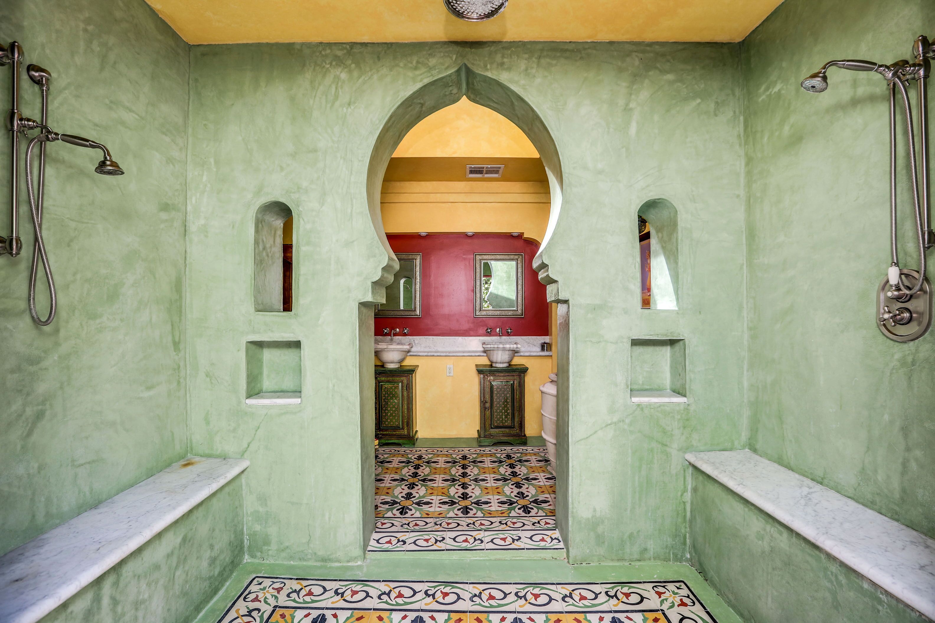 A bathroom with green walls, a tiled floor, and a red sink area.