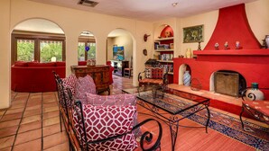 A spacious living room with a red fireplace, a red sofa, and a patterned armchair. -  MOROCCAN POOL/SPA VILLA IN PALM SPRINGS GREAT DEEPWELL NEIGHBORHOOD
  PS ID106 (Palm Springs)