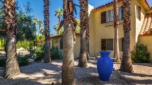 A courtyard with palm trees, a blue vase, and a building with a red-tiled roof. -  MOROCCAN POOL/SPA VILLA IN PALM SPRINGS GREAT DEEPWELL NEIGHBORHOOD
  PS ID106 (Palm Springs)