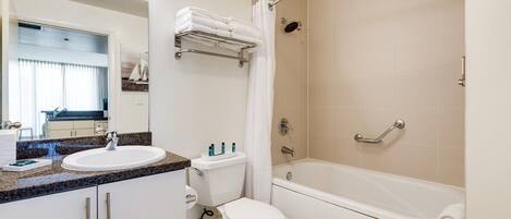 Een moderne badkamer met een bad, toilet en wastafel.