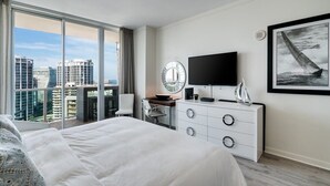 Una habitación de hotel moderna con una cama grande, un escritorio, un televisor y vistas a la ciudad.