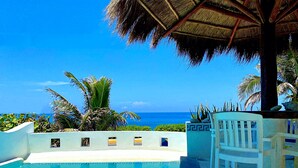 Ein Pool mit freiem Blick auf den Ozean, umgeben von Palmen und einer Struktur mit Reetdach.