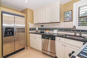 Een moderne keuken met roestvrijstalen apparatuur, witte keukenkastjes en een betegelde achterwand.