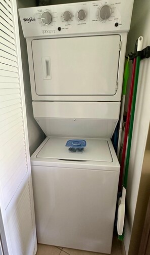 Een was- en droogcombinatie van Whirlpool met bedieningsknoppen, een start/pauzeknop en een blauwe zeepdispenser.