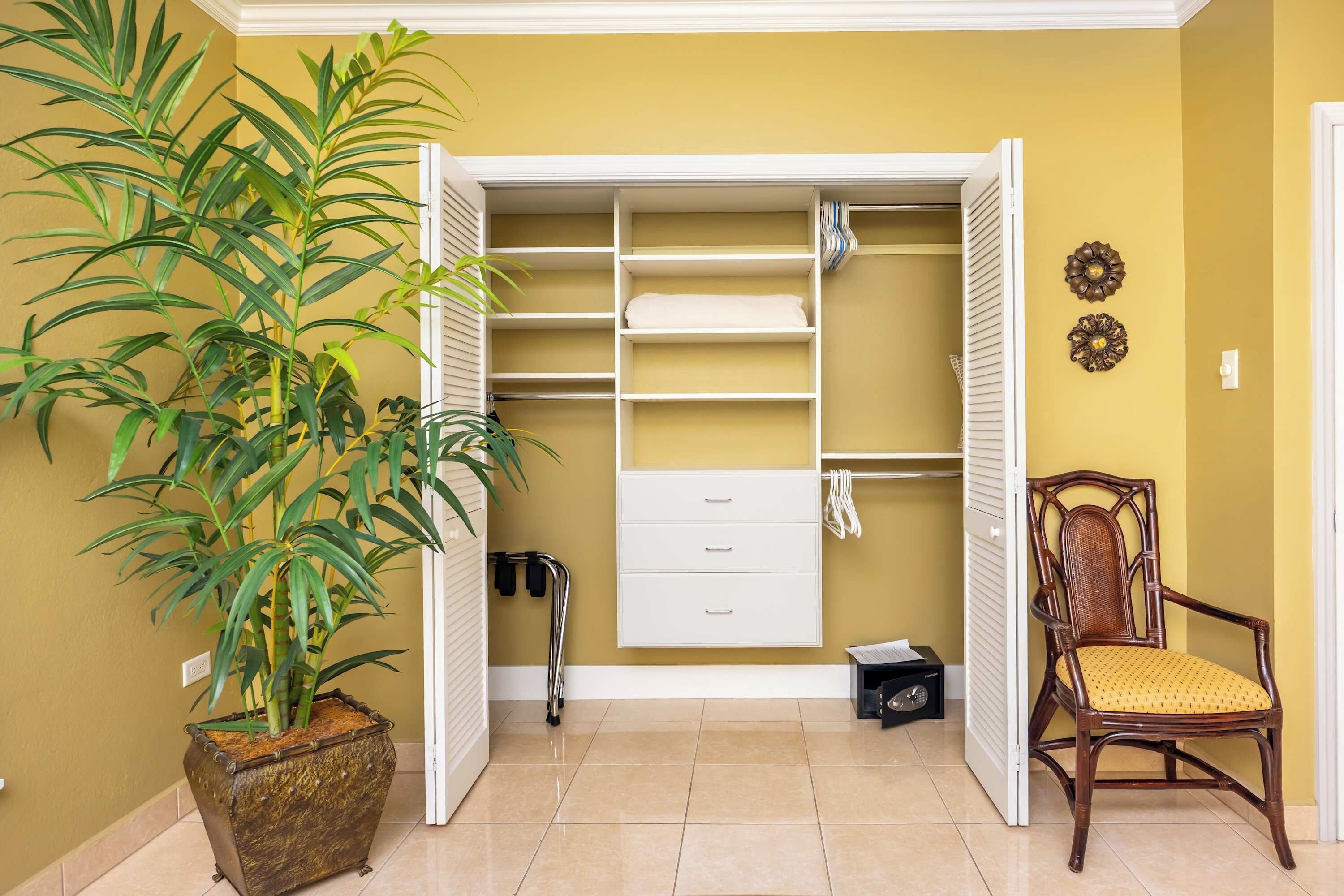 A room with a large potted plant, a wooden chair, a white storage unit with drawers, and a radiator.