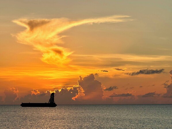 A ship on calm waters during sunset with a clear sky.