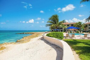A beach resort with a pool area, palm trees, and a view of the ocean.