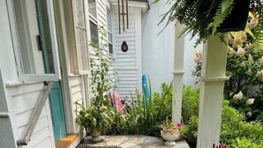 A stone-paved entrance with steps leading to a white door, surrounded by potted plants and a small garden. - Authentic 1795 Historic Homestead w/ Private Grounds for Gatherings and Retreats (Old Saybrook)