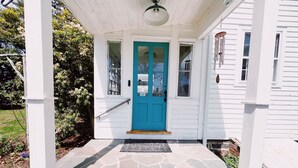 A porch with a blue door, white columns, and a stone floor. - Authentic 1795 Historic Homestead w/ Private Grounds for Gatherings and Retreats (Old Saybrook)