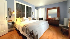 A bedroom with a large bed, wooden flooring, a dresser, a mirror, and a clock on the wall. - Authentic 1795 Historic Homestead w/ Private Grounds for Gatherings and Retreats (Old Saybrook)
