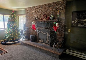 A living room with a fireplace, a Christmas tree, and a fireplace screen.