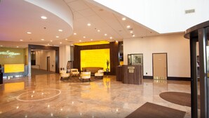 A hotel lobby with a reception desk, seating area, and a security desk.