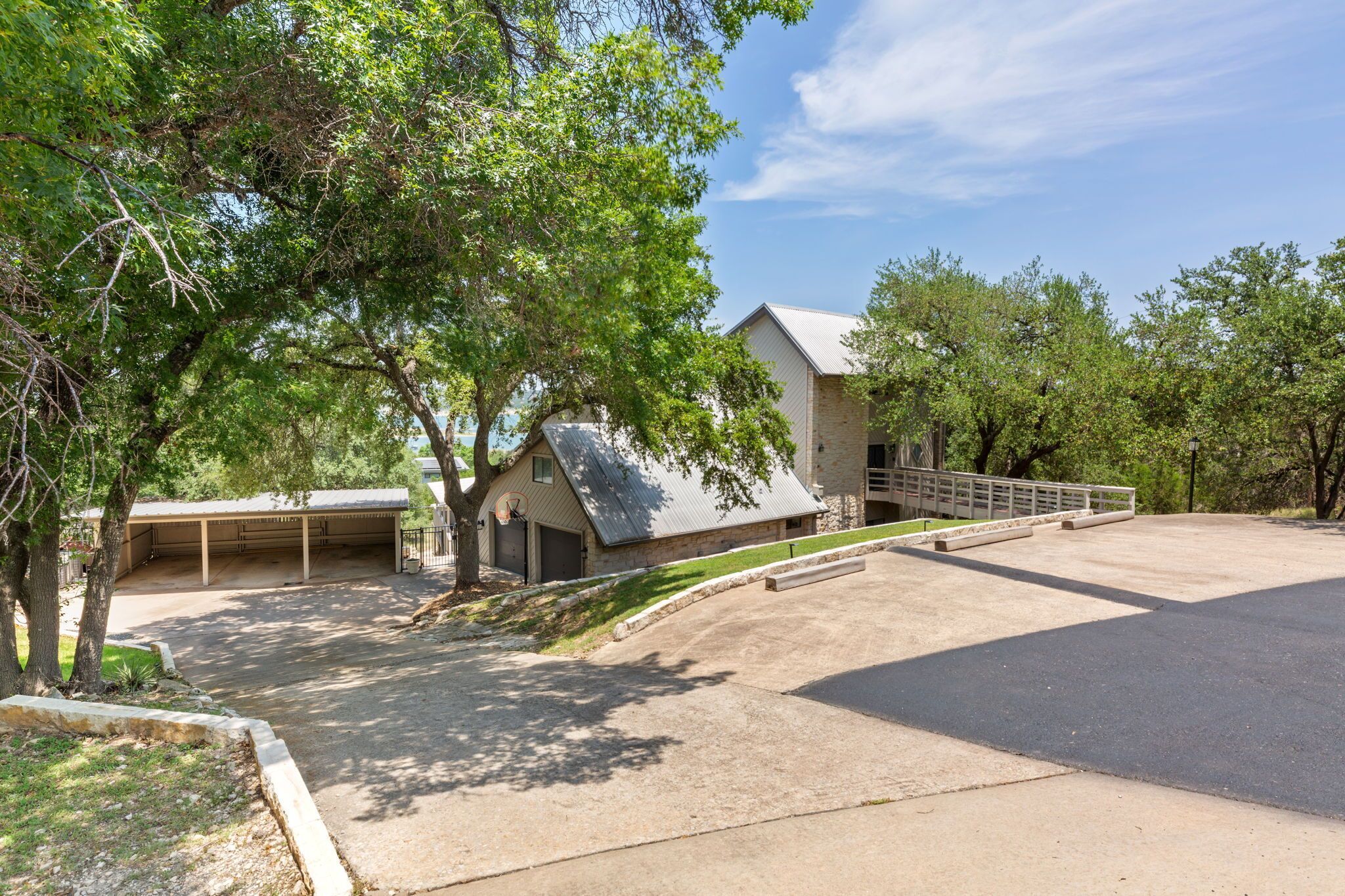 A residential property with a covered garage, a detached garage, and a driveway leading to a house with a sloped roof.