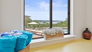A room with a large window overlooking a pool and greenery. There are towels and a vase on the windowsill. - Lake Travis Oasis, Pool, Hot Tub, Lake Views, Near Marinas & Austin! (Austin)