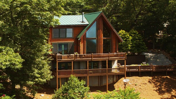 A cabin with a green roof, a balcony, and a view of a forested area. - Mountain top overlooking lake, Hot Tub, Pickleball, Yukon Fire Pit, 5 STAR, PETS (Waleska)