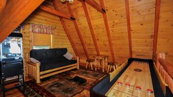 Relax in this cabin-style room with a wooden floor, patterned rug, and cozy sofa.