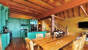 A wooden cabin interior with a dining area, kitchen, and staircase. - Mountain top overlooking lake, Hot Tub, Pickleball, Yukon Fire Pit, 5 STAR, PETS (Waleska)