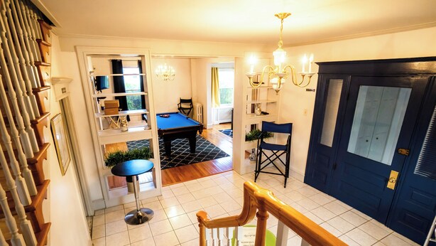 A spacious room with a billiards table, a green chair, and a blue chair.
