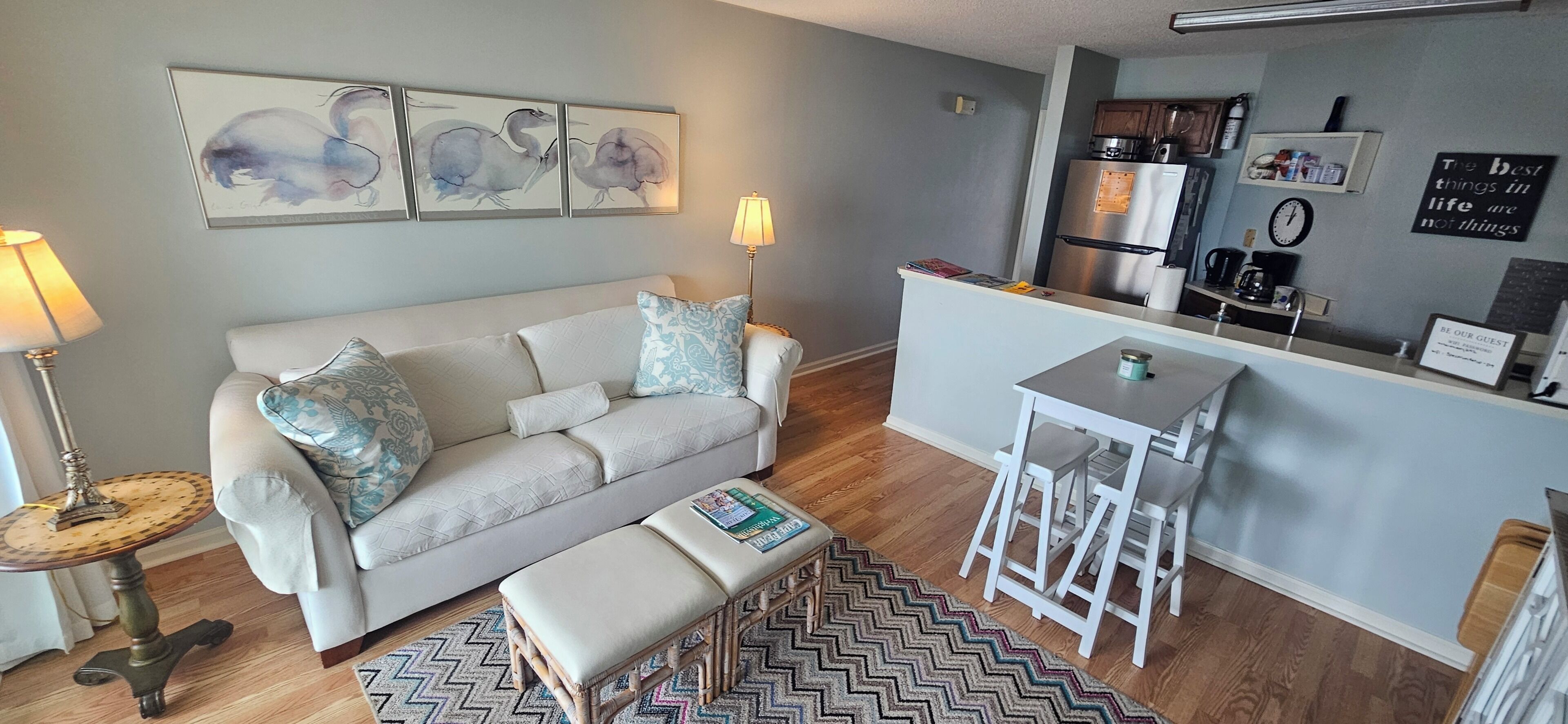 A compact living space with a sofa, a small table, a bench, and a kitchen area.