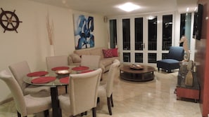 A living room with a round table, beige sofa, and a blue armchair.